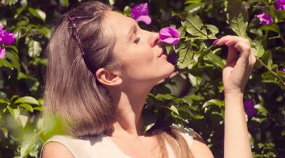8 Ways to Start Simplifying Life Today. Woman standing outside smelling a purple flower.