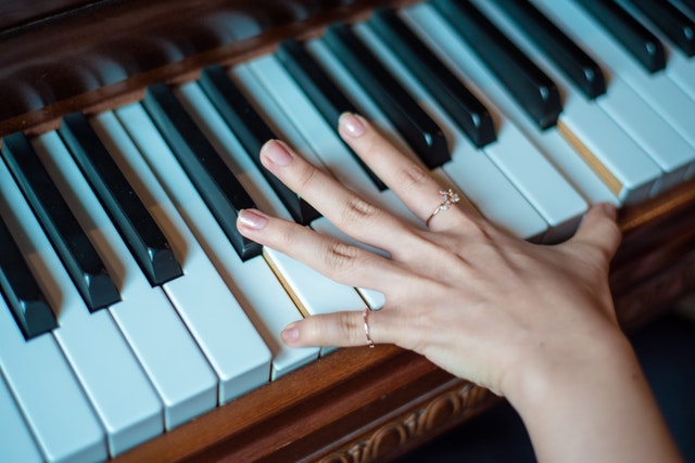 Female hand playing piano as a stress relief activity. My Fit Habits