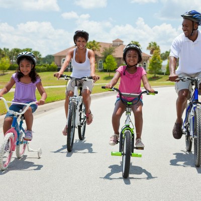 Best Outdoor Activities for the Whole Family. Family of four riding bicycles outside while wearing safety helmets.