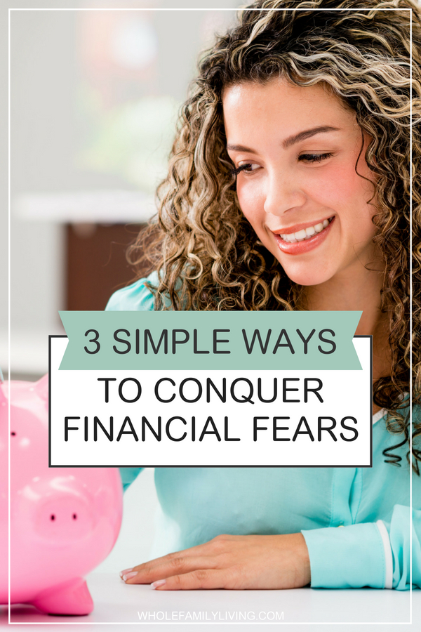 Easy ways to conquer financial fears. Woman smiling while looking at a pink piggy bank.