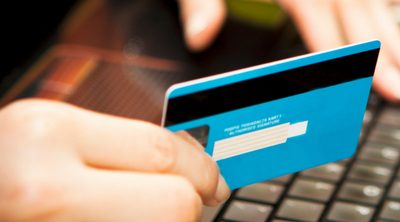 How to Protect Your Family From Identity Theft. Person holding a credit card in hand to pay for an online purchase.