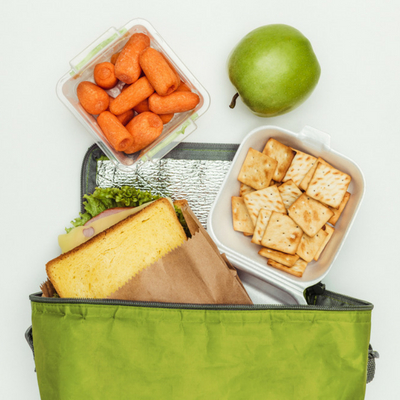Simple Tips for Eating Healthy on the Go - Whole Family Living. Green lunch bag with assortment of healthy snacks.