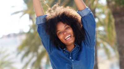 Happy African-American woman with arms raised overhead in joy. Wellness Challenges to Improve Your Health - Whole Family Living