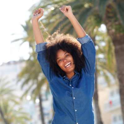Happy African-American woman with arms raised overhead in joy. Wellness Challenges to Improve Your Health - Whole Family Living
